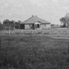 faded photo of school building with pyramid shaped roof in field