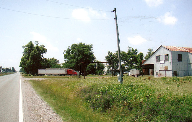 country road with semi-truck and trailer in field with metal barn