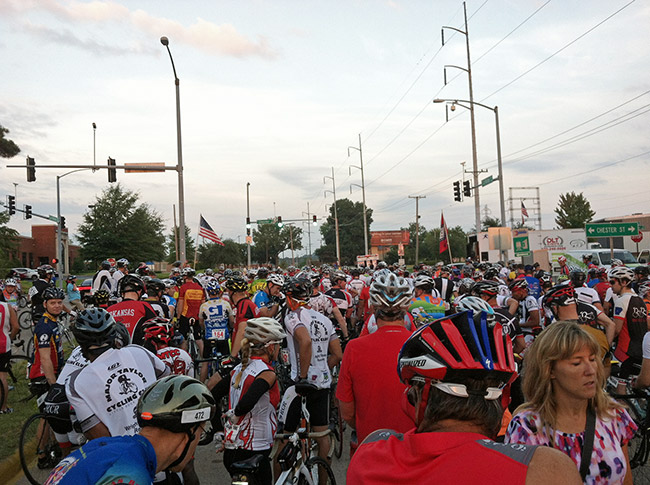 Crowd of people on bicycles with helmets on city street