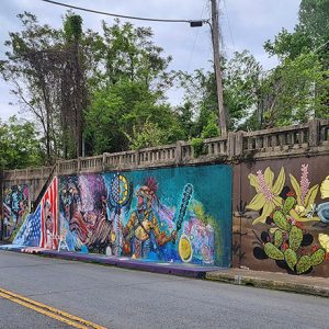 Colorful multicolored artwork on concrete viaduct wall on two-lane road with bridge over it