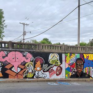 Anthropomorphic brain busting from cardboard box and African-American figures painted on concrete viaduct wall with railing