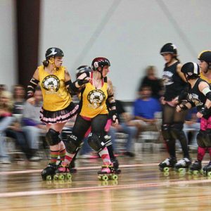 Young white women in yellow shirts racing on roller skates