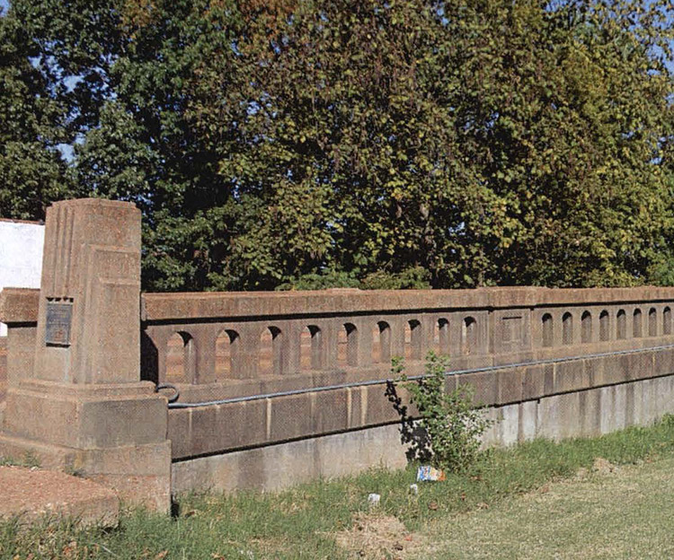 Concrete bridge railing and monument with plaque on it