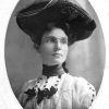 Portrait of a woman in glasses wearing a large decorative woven hat and matching dress
