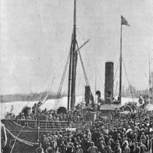 Crowd of people gathered at boat dock and aboard a ship with horse-drawn cart in the foreground