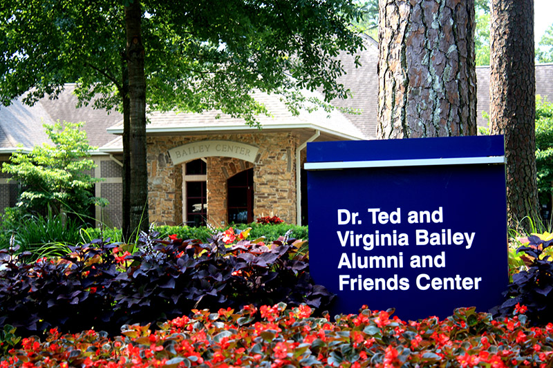 Building with blue sign "Dr. Ted and Virginia Bailey Alumni and Friends Center"