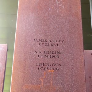 Rust-colored metal rectangle engraved with names and locations