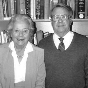Old white woman and white man in glasses with bookshelf