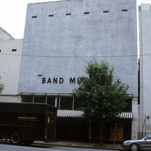 UPS truck tree and car on street in front of storefront building that says "the band museum" on the front