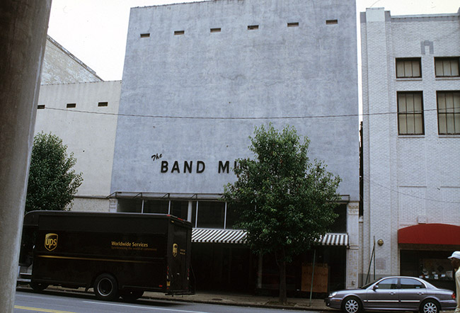 UPS truck tree and car on street in front of storefront building that says "the band museum" on the front