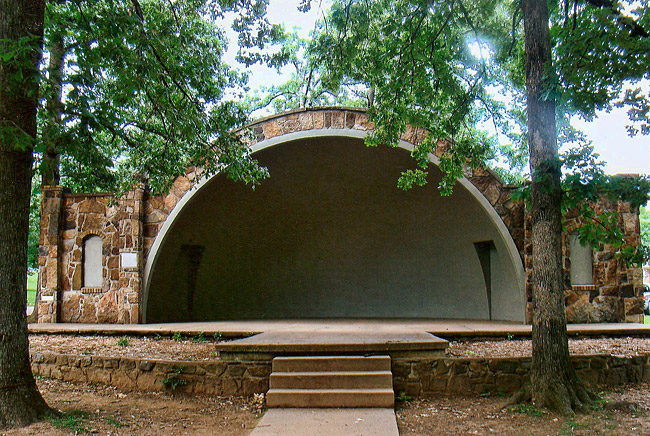 stone and concrete hemispherical stage outside with trees