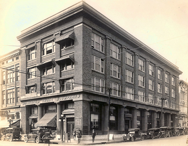Four-story building on street corner with people and cars
