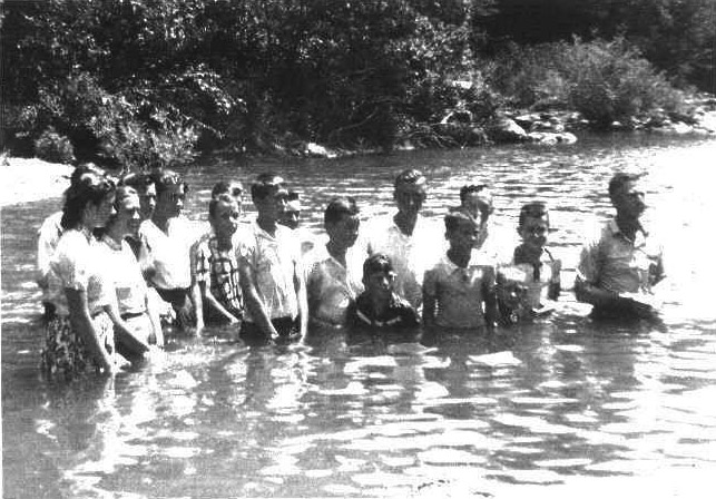 White men women and children standing in river