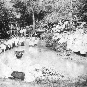 Large group of people surrounding small body of water