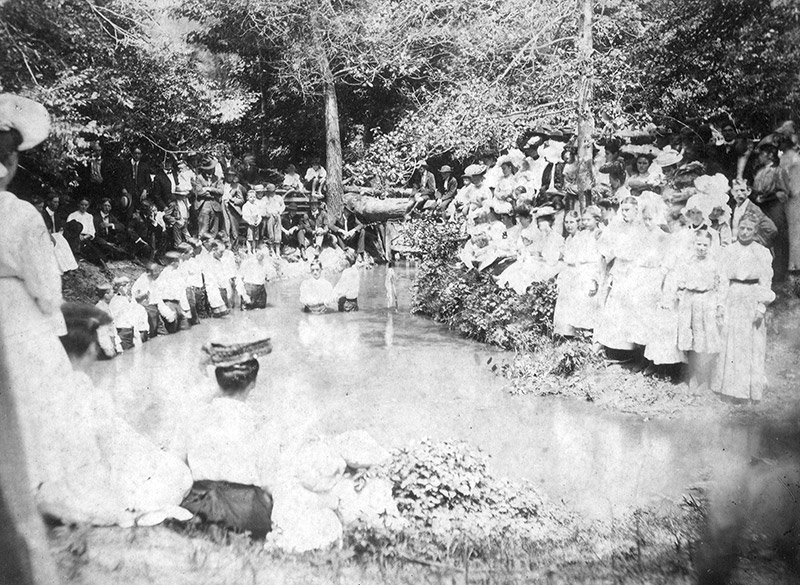 Large group of people surrounding small body of water