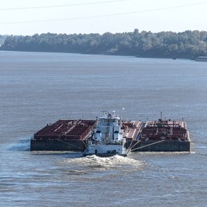 Tug boat in the center of river pushing a barge