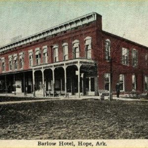Two story red brick building with covered porch and street on post card