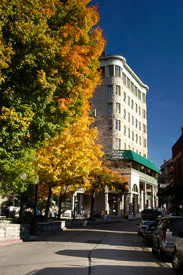 Street with multistory hotel building, parked cars and autumn foliage