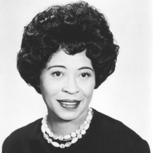 African-American woman wearing dark colored dress with double strain shell necklace