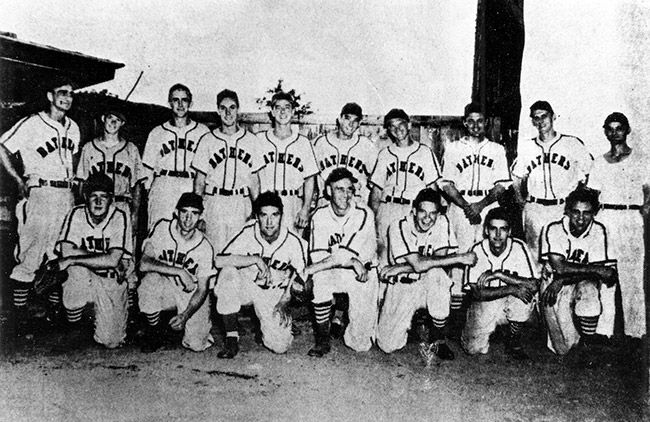 Group of young white men in baseball uniforms posing on field