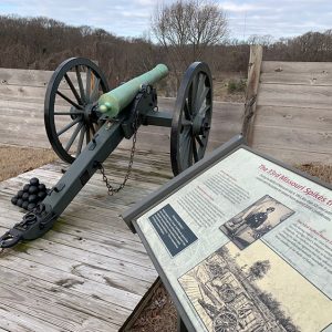 Cannon with balls and interpretation panel in recreated fort