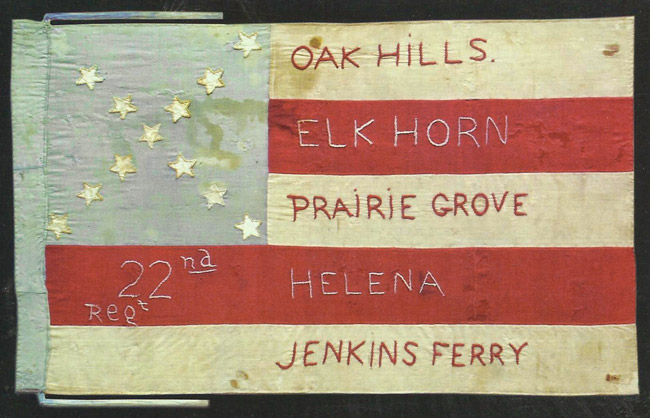 Red white and blue flag with stars in X formation and text stitched on the stripes saying 'Oak Hills Elk Horn Prairie Grove 22nd Regt. Helena Jenkins Ferry"