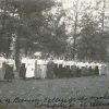 group of white girls in white shirts and long skirts standing in line two-by-two