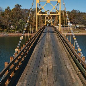 wooden bridge with yellow trusses over a body of water