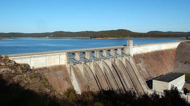 distant elevated view of dam holding back water and the dry spillway and embankment