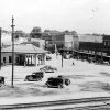 Busy streets and gas station with buildings in the background and railroad tracks in the foreground