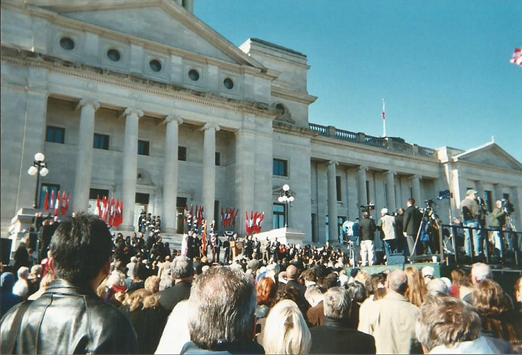 Large mixed crowd on steps of multistory building with large dome and stone walls