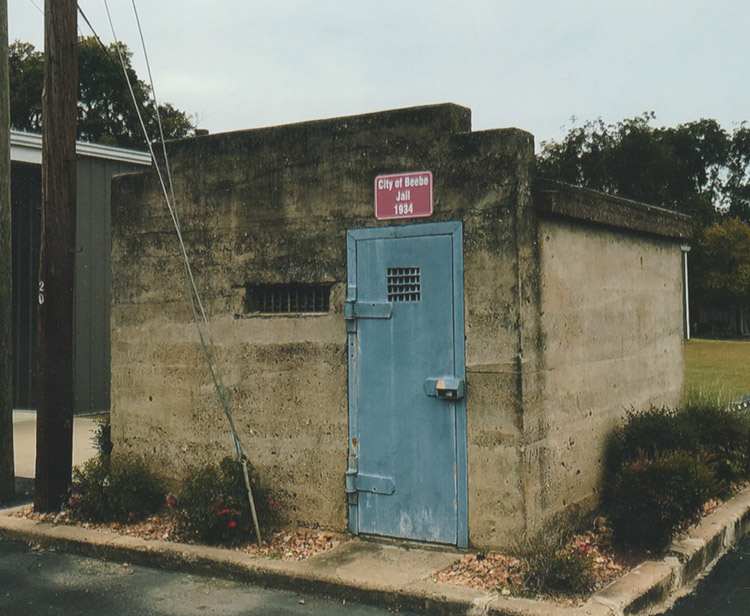 Small concrete building with blue metal door under red sign and tiny windows