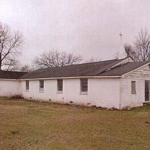 Side view of cinderblock church building with cross on small steeple