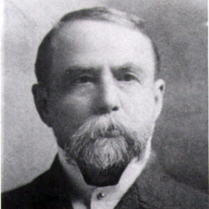 White man with long mustache and short beard in suit