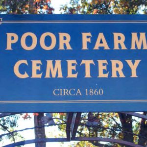 "Poor Farm Cemetery Circa 1860" sign with gold lettering on blue background