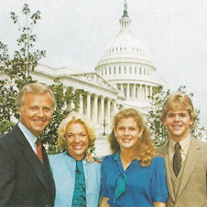 Two white men and their wives at the U.S. Capitol with text on card