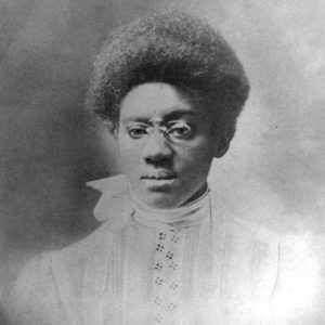 African-American woman with glasses in high-collared lace dress