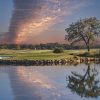 sunset with linear cloud formation over golf course and water hazard