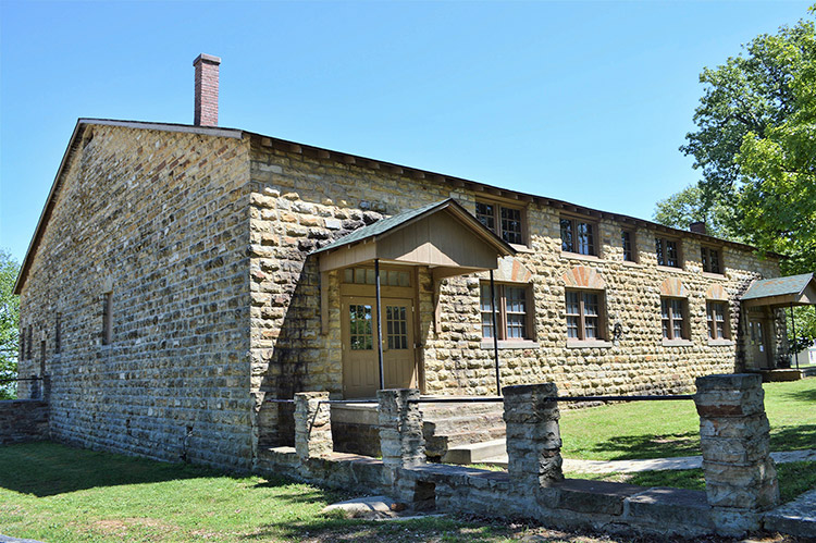 Brick building with two covered porches and wall with brick columns