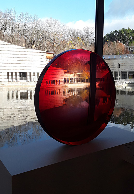 Modern buildings and pool seen through large red lens before window