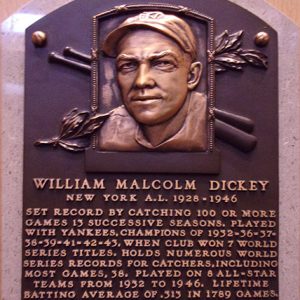 Bust of white man with baseball cap on plaque with bats and leaves above text section