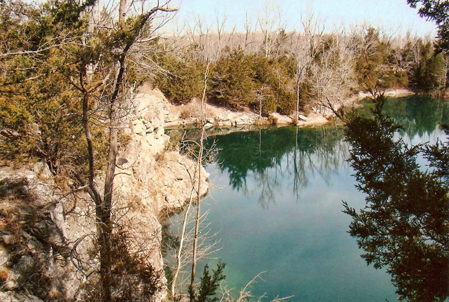 Flooded rock quarry surrounded by trees
