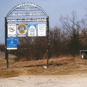 Metal arch frame "Welcome to Black Rock Home of the Zebras" sign with smaller church and Lion's club signs on it