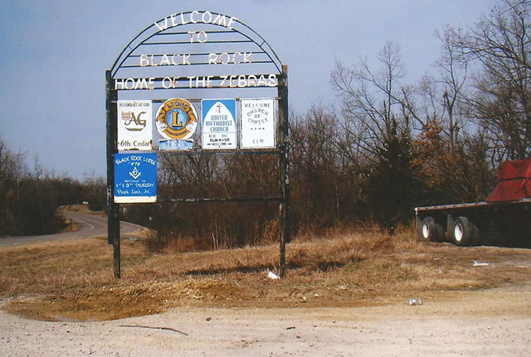 Metal arch frame "Welcome to Black Rock Home of the Zebras" sign with smaller church and Lion's club signs on it