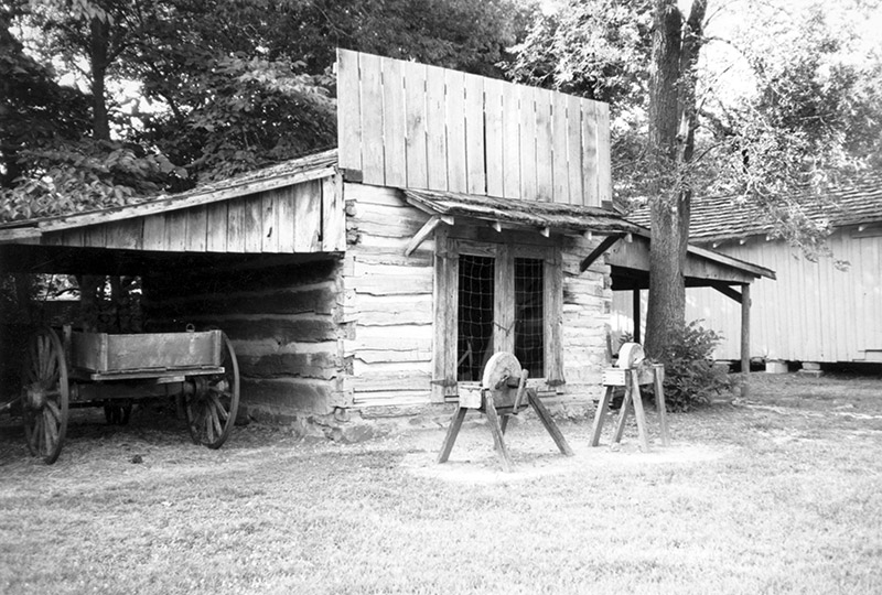 Small log building with buggy and two grinding wheels