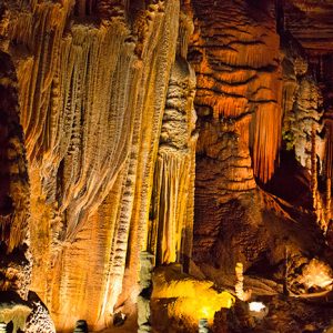artificially lit cave with striated stalactites