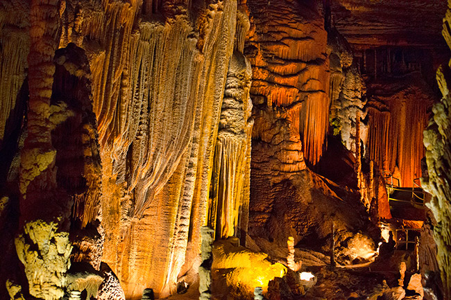 artificially lit cave with striated stalactites