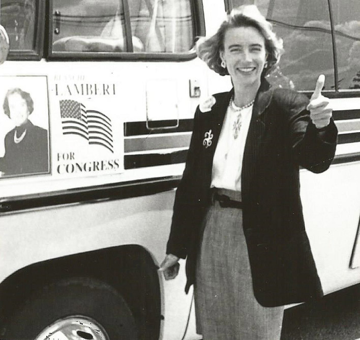 White woman giving the "thumbs-up" by campaign bus