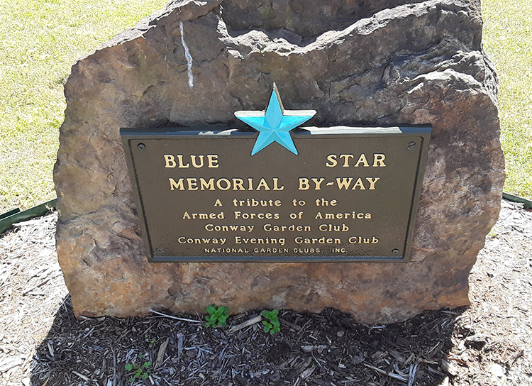 "Blue Star Memorial By Way" plaque on large rock in flower bed