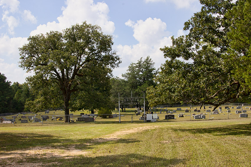 Fenced-in rural cemetery with "Ebenezer Cemetery" sign over double gates